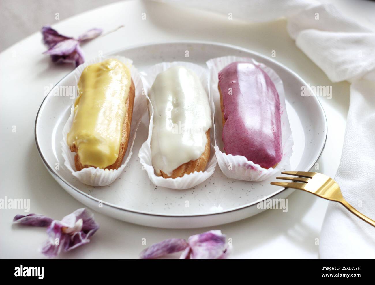 Three eclairs with different fillings lie in a plate Stock Photo