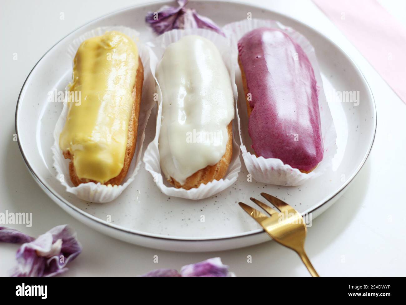 Three eclairs with different fillings lie in a plate Stock Photo