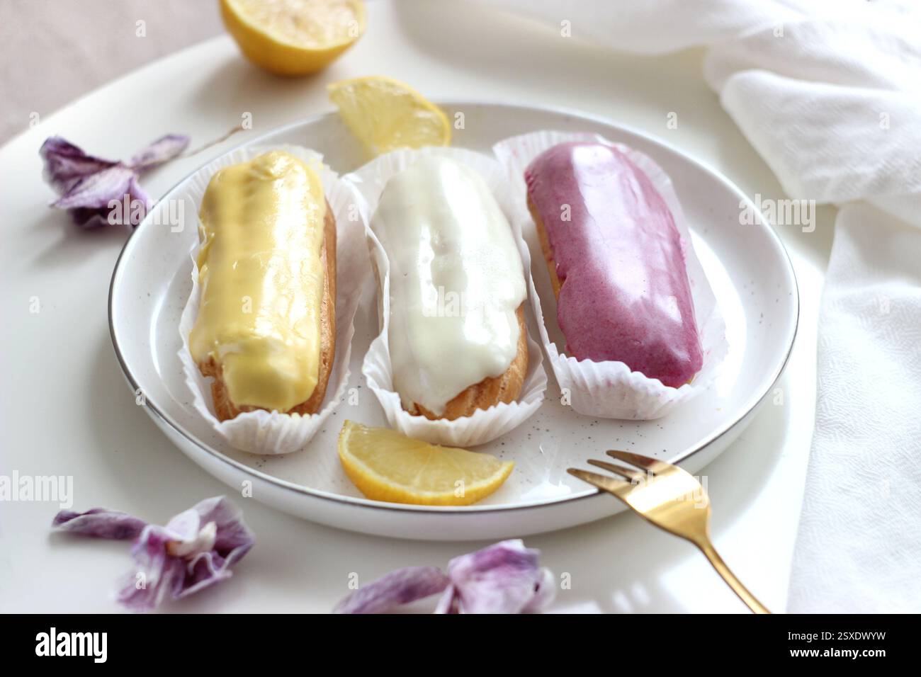 Three eclairs with different fillings lie in a plate Stock Photo
