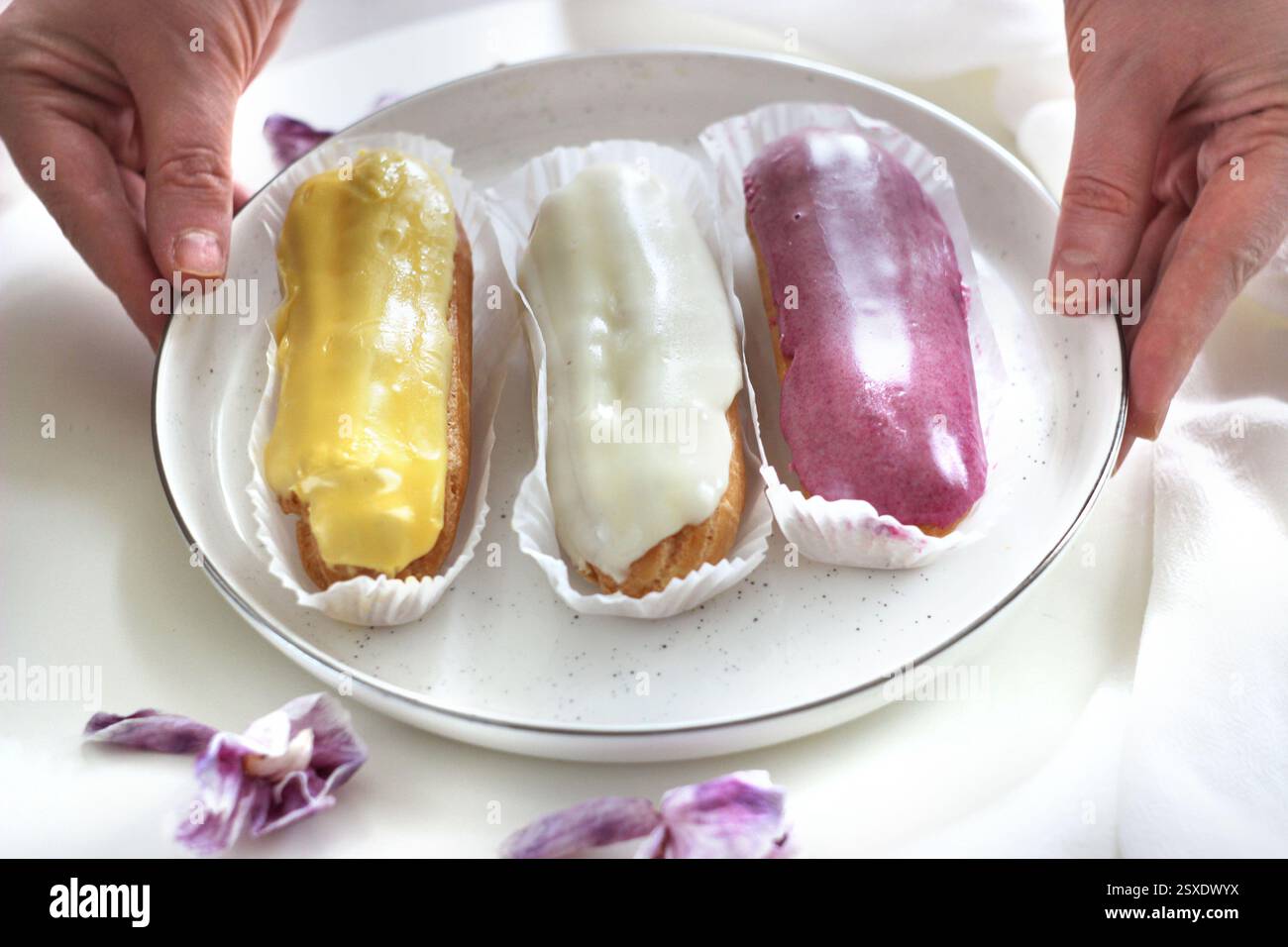 Three eclairs with different fillings lie in a plate Stock Photo