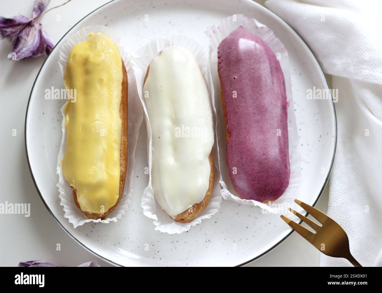 Three eclairs with different fillings lie in a plate Stock Photo