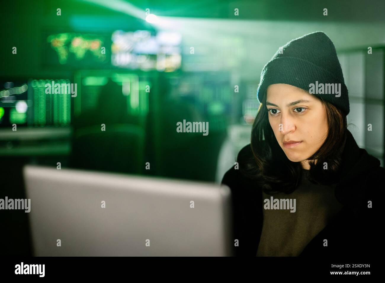 Female young hacker working on computer in dark room programming code Stock Photo