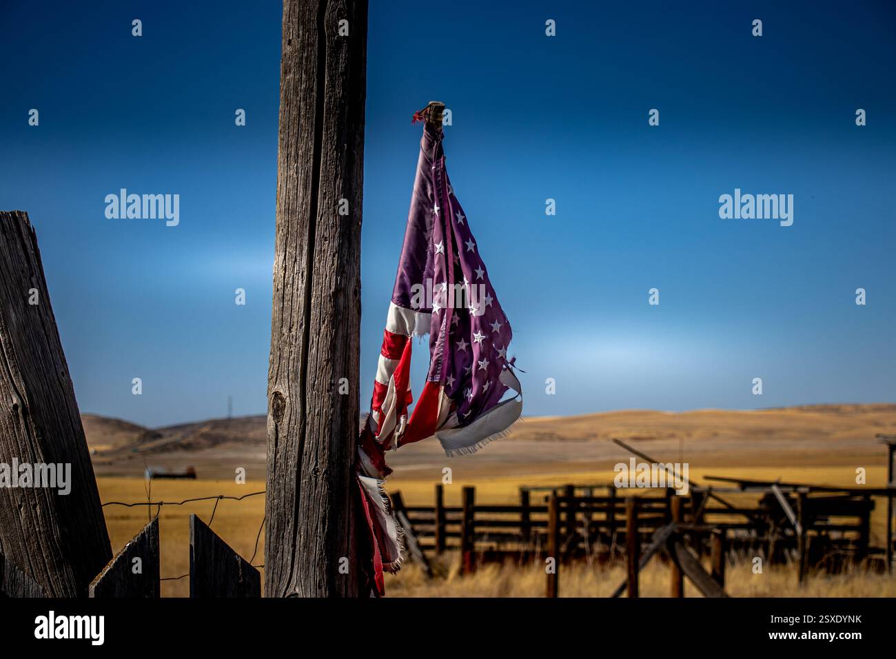 Tattered American Flag on Rural Fence Post Stock Photo