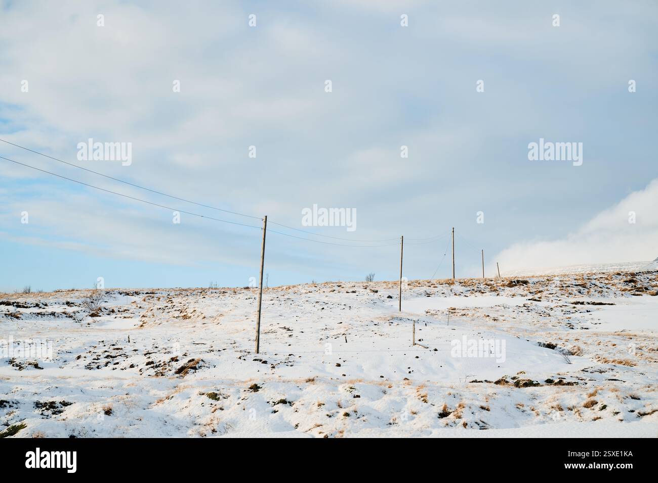 Power lines crossing snowy icelandic landscape under cloudy sky Stock ...