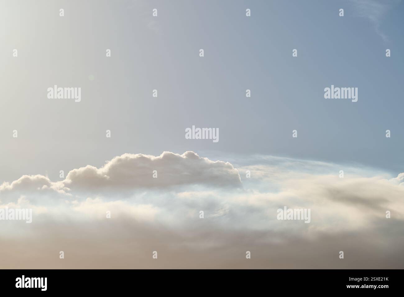Sunlight shining through white clouds in blue sky Stock Photo