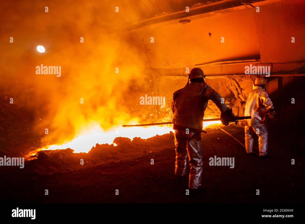 Side Slag Furnace workers clean the slag buildup on a side of the slag groove in ...