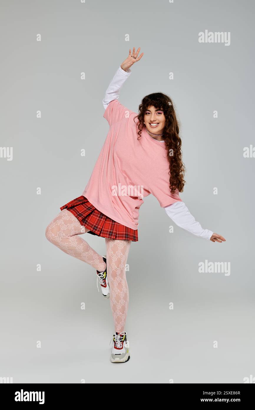 A young woman with curly hair poses playfully in her stylish outfit ...