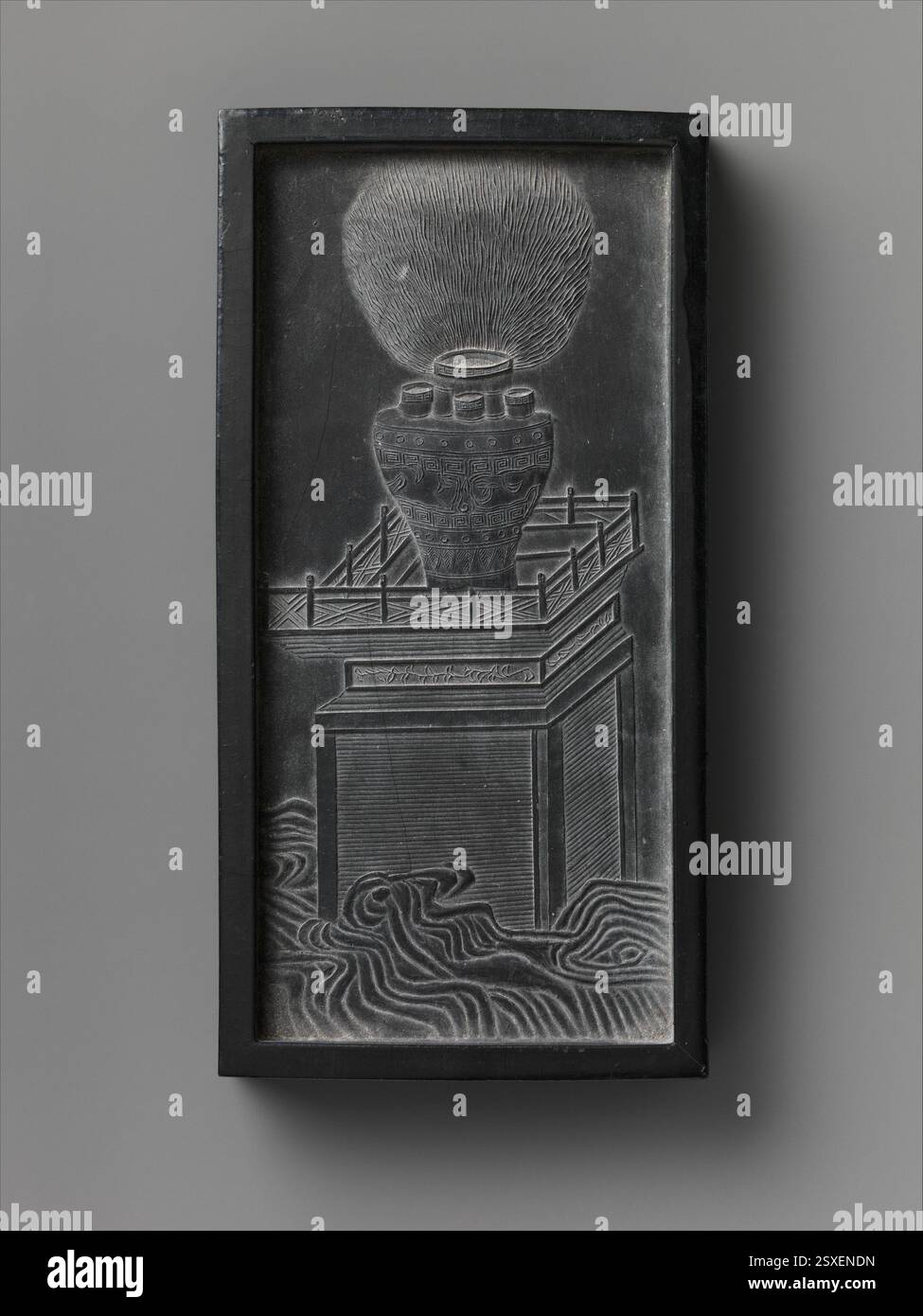 This inkstone from China, dated 1688, is depicted with a vase on a table. The inkstone was an essential writing tool for scholars, and its elegant design reflects the importance of calligraphy and artistic expression in Chinese culture during the late 17th century. Stock Photo