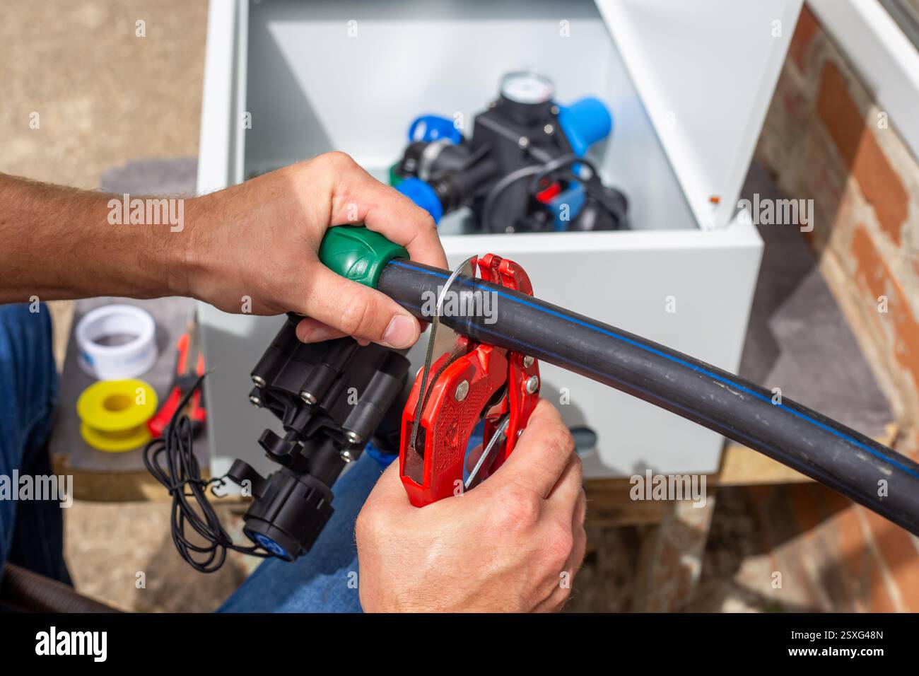Installation of a drip irrigation system for a garden. A man cuts a ...