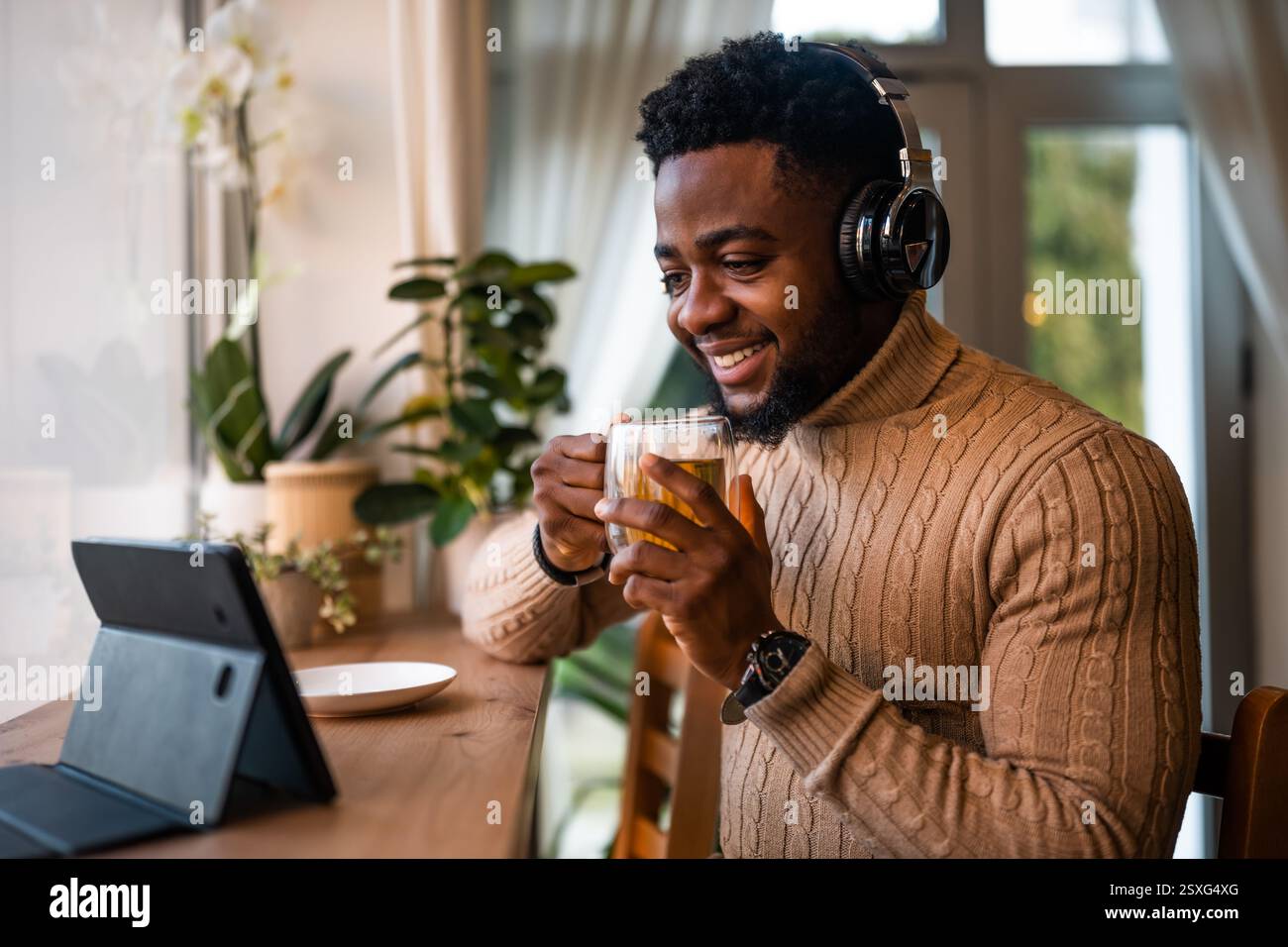 Freelancer using digital and having video call in bar. He is drinking tea. Stock Photo