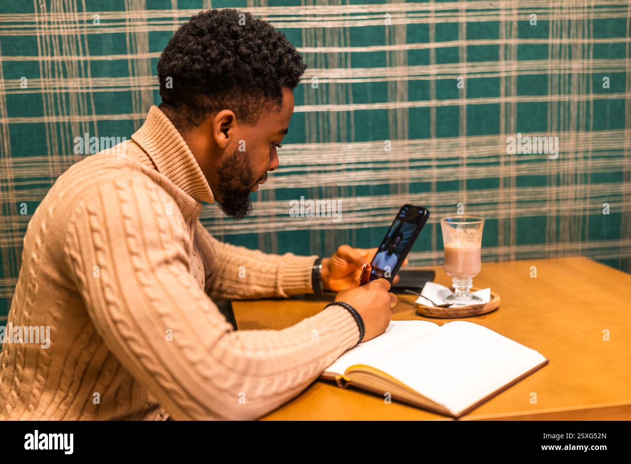 Freelancer using smartphone and notepad. He is sitting in bar and making plans for work. Stock Photo
