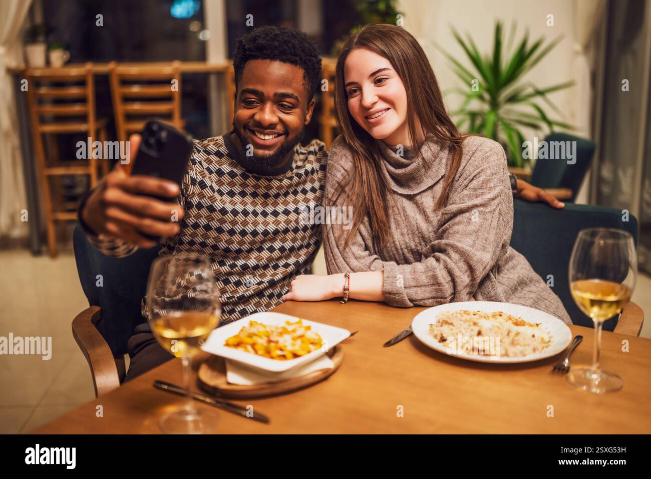 Two friends are having dinner at restaurant. They are taking selfie. Stock Photo