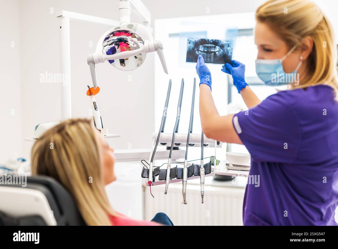 Dentist is examining x-ray image of jaw and teeth with her patient. Stock Photo