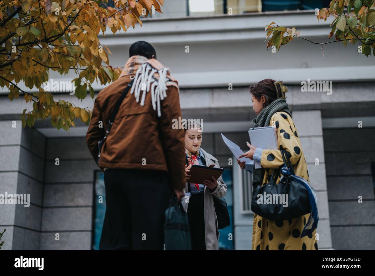 Multiracial people collaborating outdoors in autumn setting with documents Stock Photo