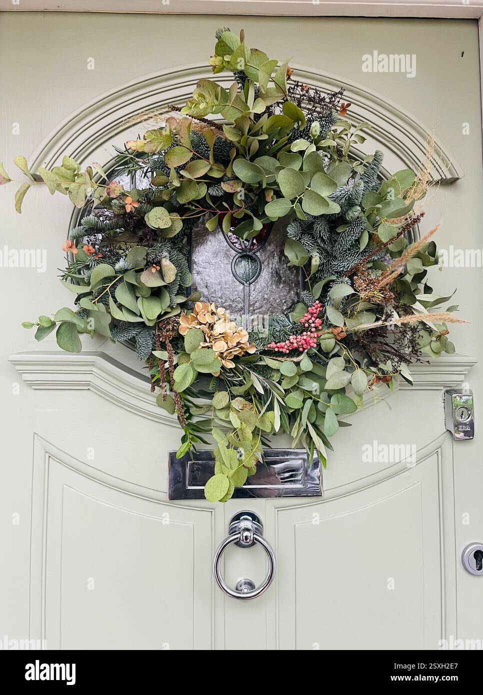 Decorating our front door with a Christmas wreath December 2024 - Smartphone Captured Stock Image