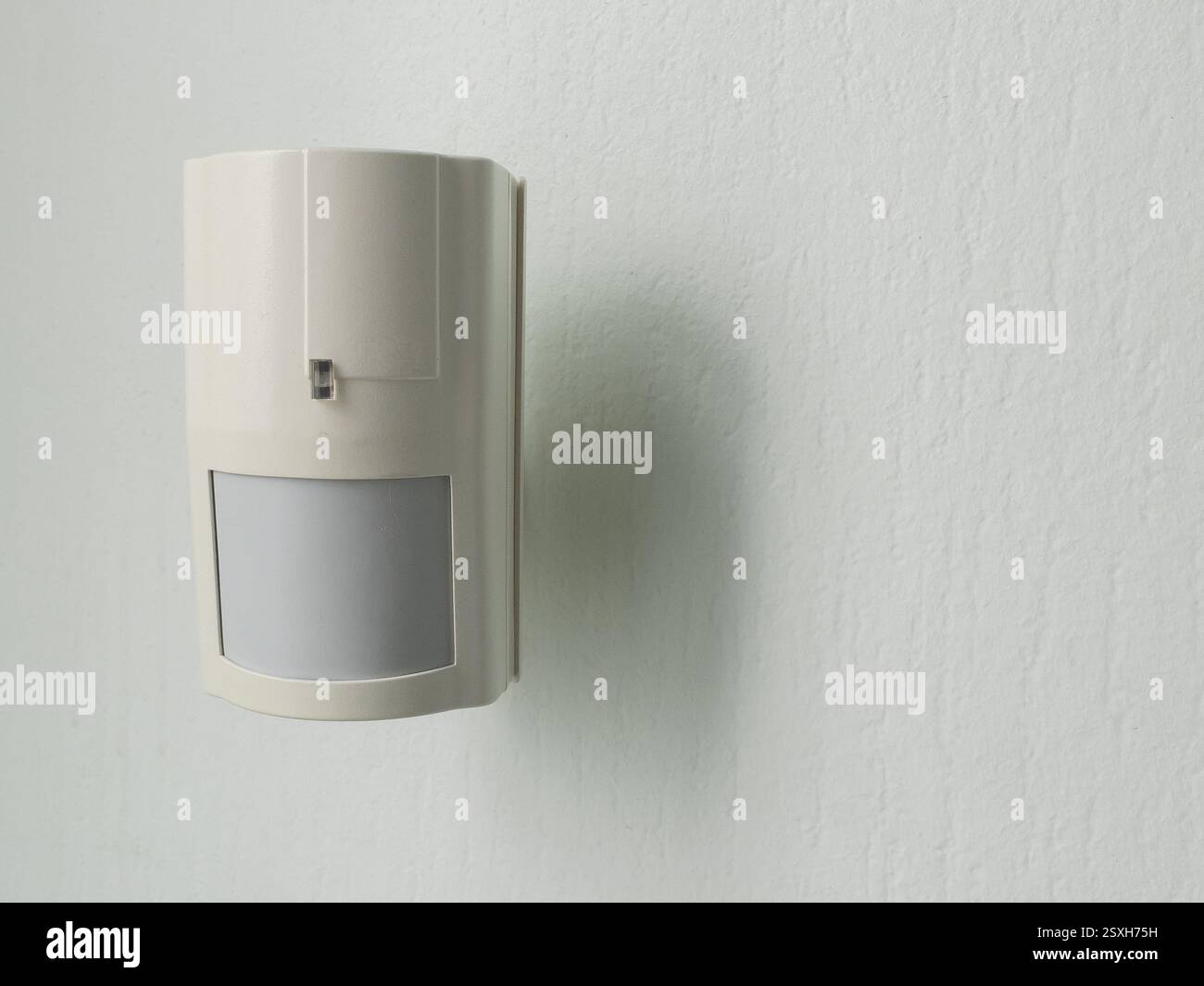 Modern motion sensor on wall indoors Stock Photo