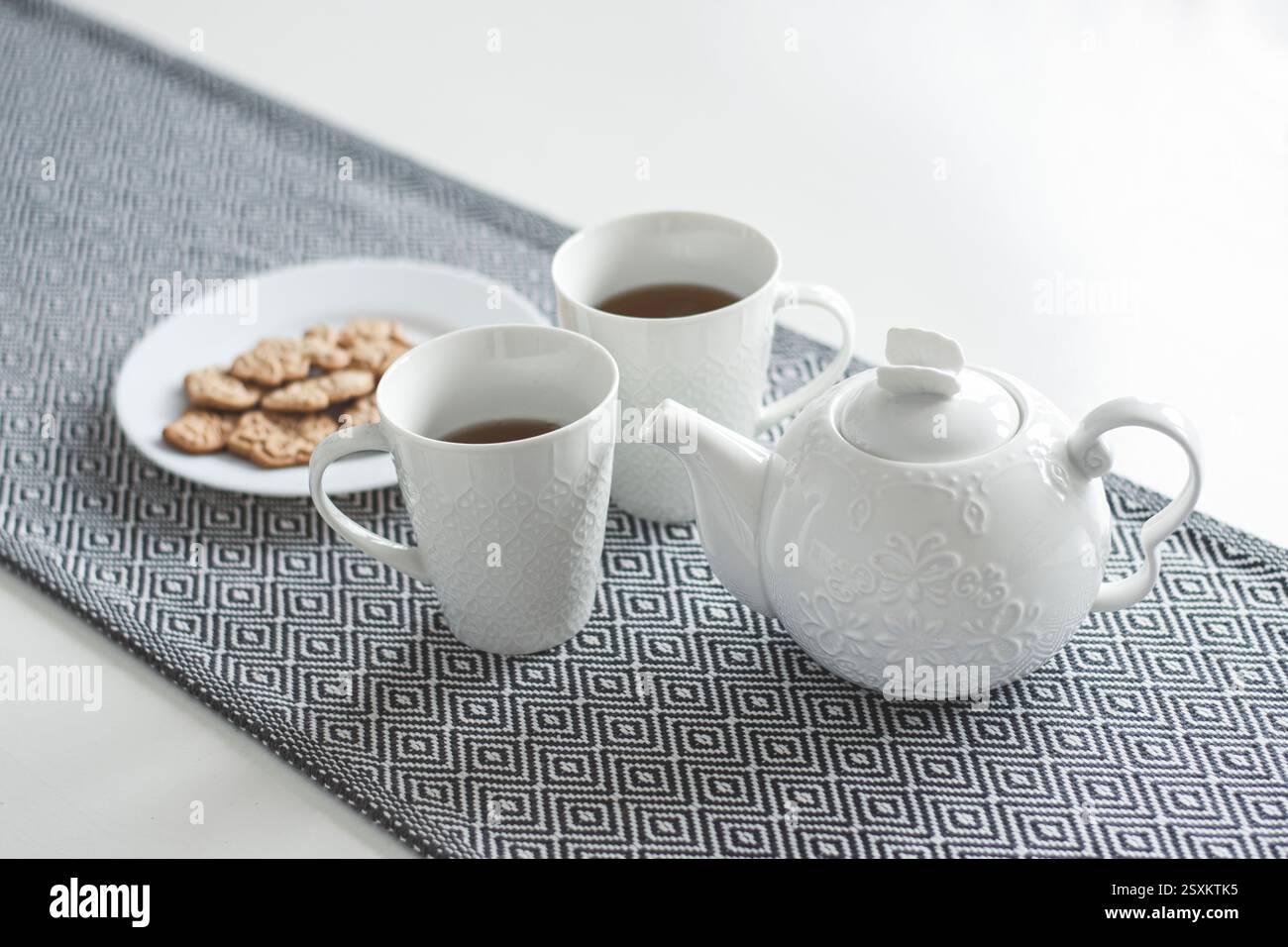 White ceramic teapot, tea and cookies on the table Stock Photo