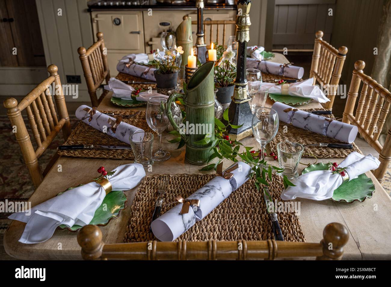 Christmas crackers and napkins at place settings with lit candles in renovated East Sussex Tudor farmhouse dating from 1540, England, UK. Stock Photo