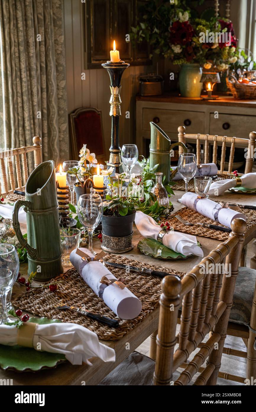 Christmas crackers and napkins at place settings with lit candles in renovated East Sussex Tudor farmhouse dating from 1540, England, UK. Stock Photo