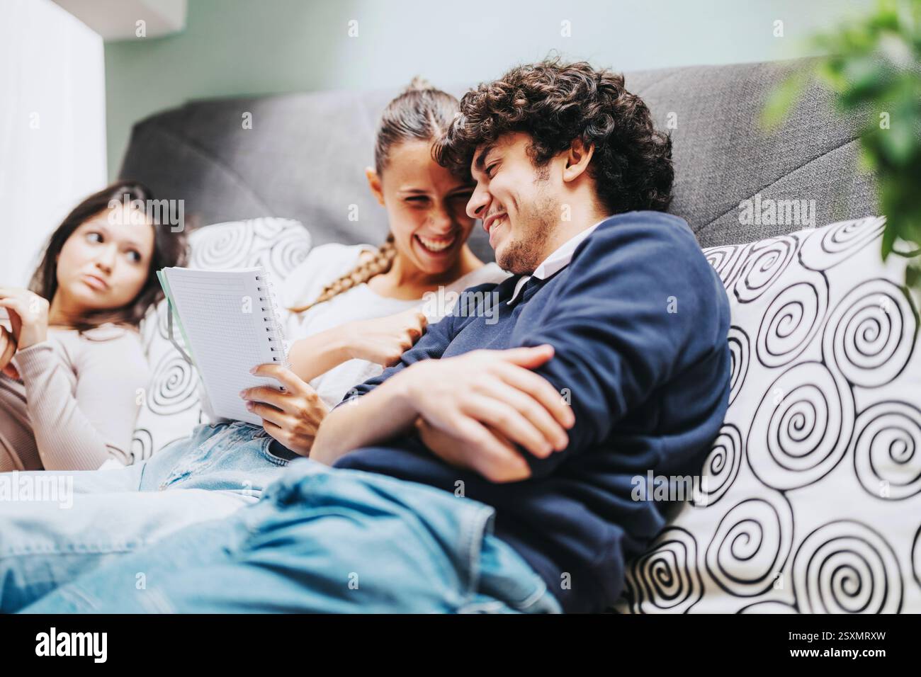 Friends sitting on couch sharing a laugh while studying together Stock Photo