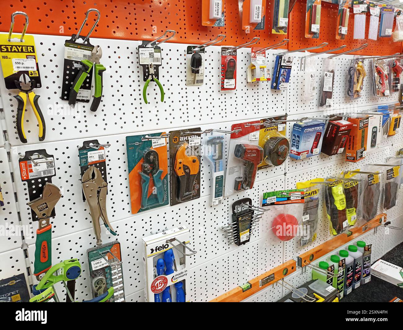 Various tools displayed on pegboard in hardware store aisle. Stock Photo