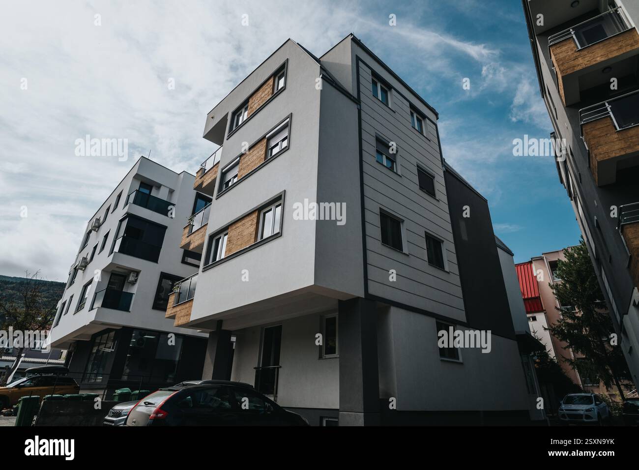Modern apartment building with balconies and cars parked on the street ...