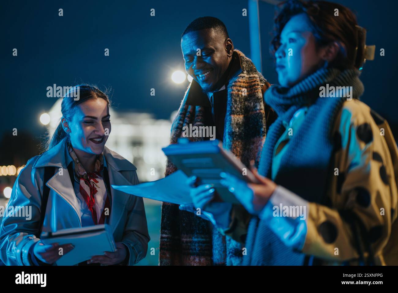 Multiracial people collaborating outdoors during nighttime Stock Photo