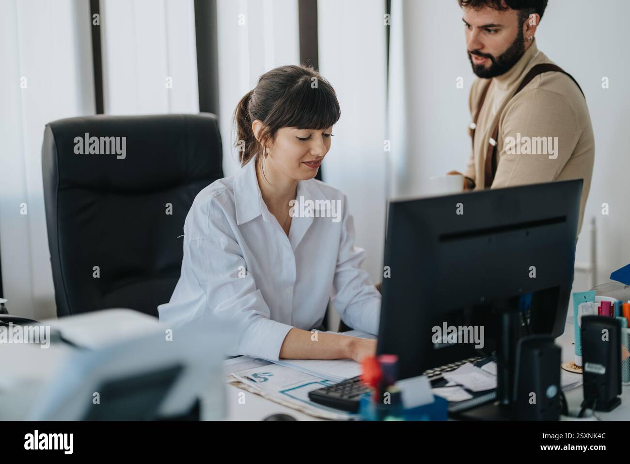 Office colleagues collaborating on a project while reviewing computer data Stock Photo