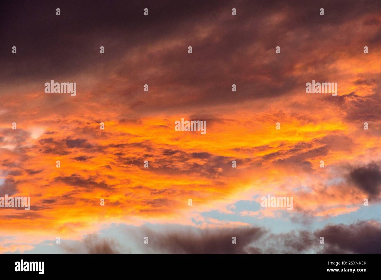 Heavy storm clouds lit underneath by setting sun - red sky at night. Stock Photo