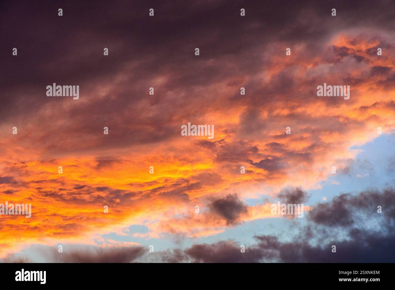 Heavy storm clouds lit underneath by setting sun - red sky at night. Stock Photo