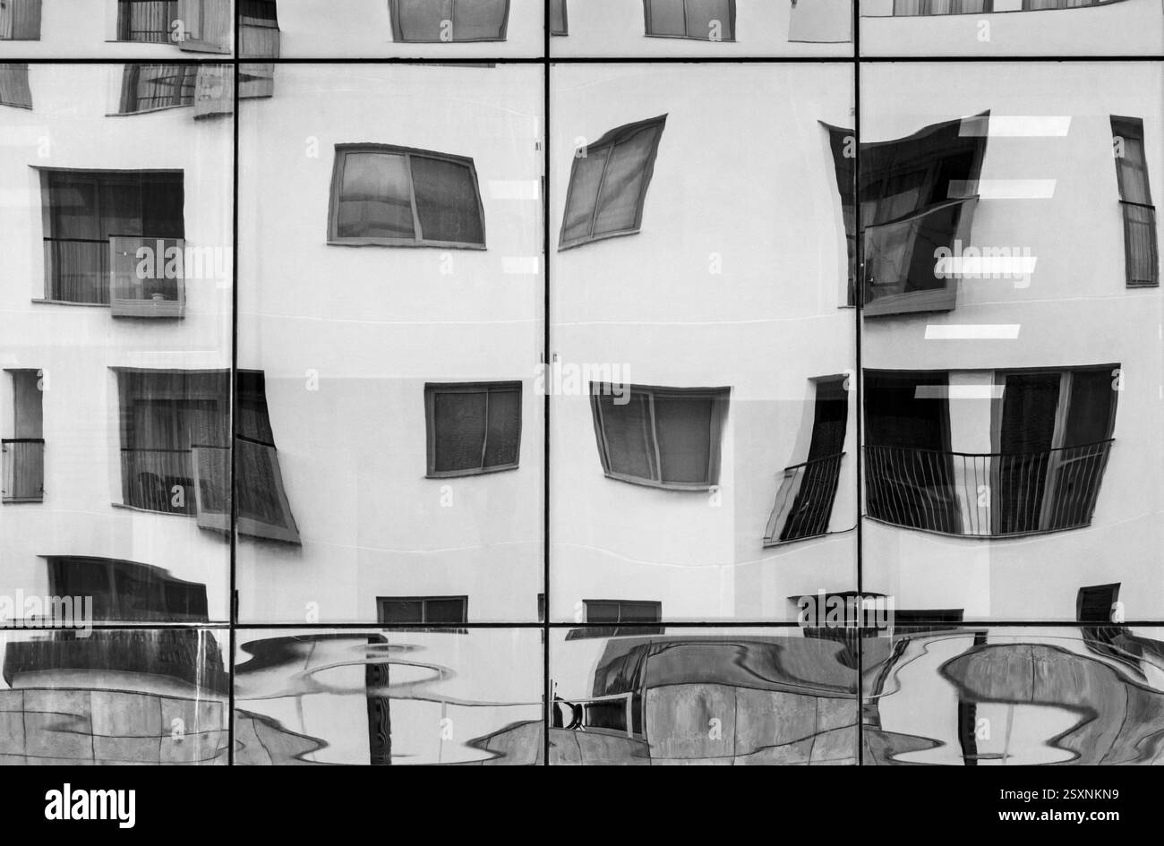 Office block windows reflecting an apartment block in Sliema, Malta. Monochrome image. Stock Photo