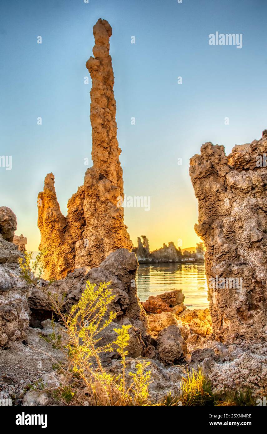 Rock formation with a tall pillar in the middle. The pillar is surrounded by rocks and there is a body of water in the background Stock Photo