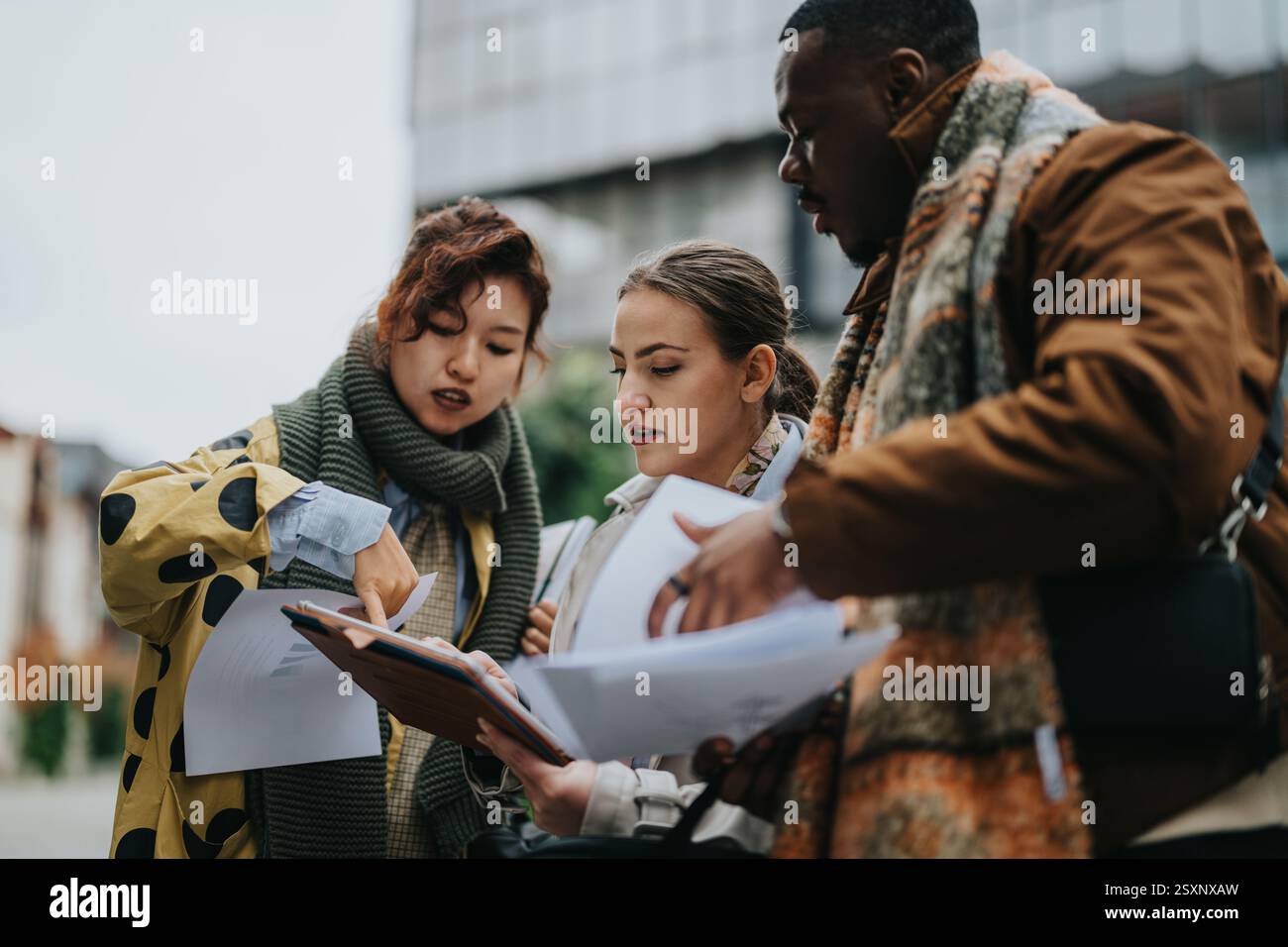 Multiracial Professionals Collaborating on a Document Outdoors While Brainstorming Ideas Stock Photo