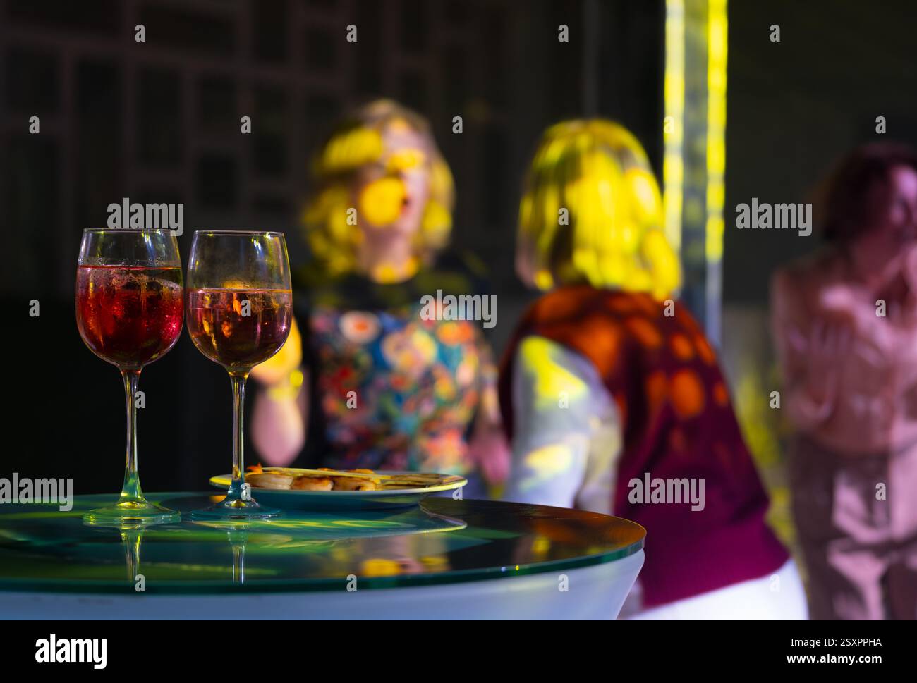 Glasses of wine with group enjoying lively conversation at indoor ...