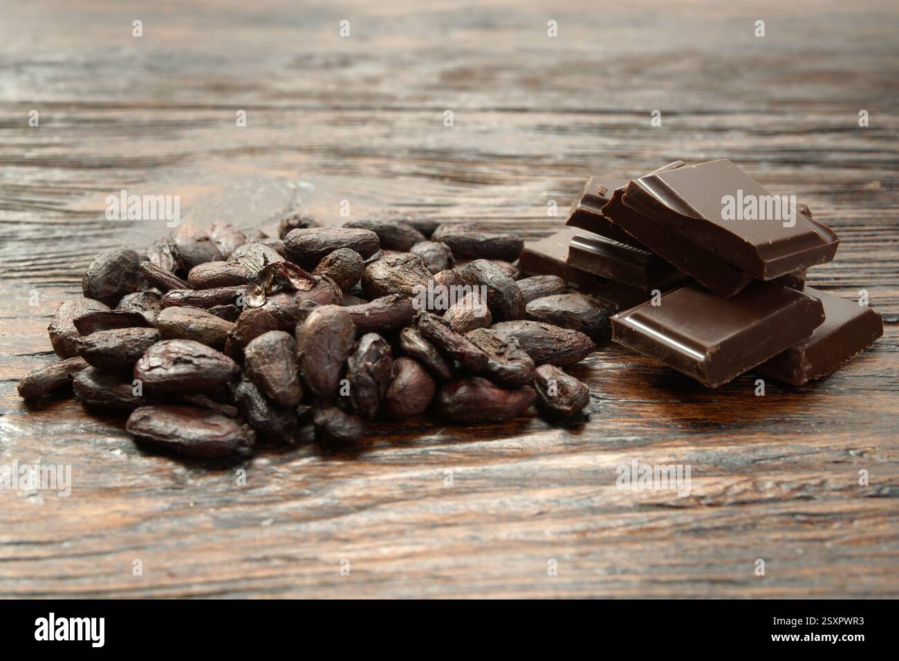 Broken dark chocolate and cocoa beans on the table Stock Photo