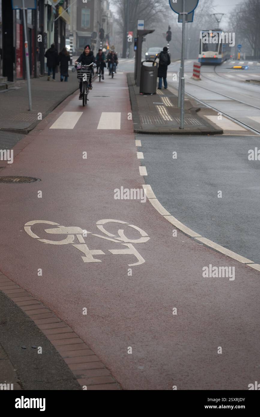 Cyclist using a dedicated bike path in a city environment, promoting sustainable transportation. Bicycle lane. Amsterdam Stock Photo