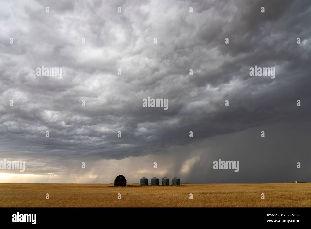 Ominous supercell storm clouds gathering over a farm with grain silos ...