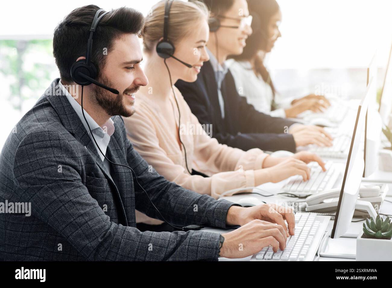 Telemarketing or hotline operators working with computers at light office Stock Photo