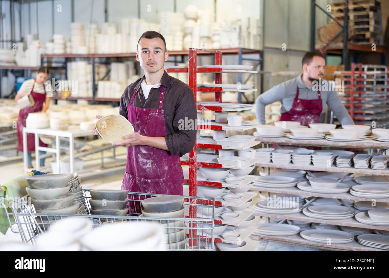 Enthusiastic ceramicist demonstrating handcrafted plates in ceramic studio Stock Photo