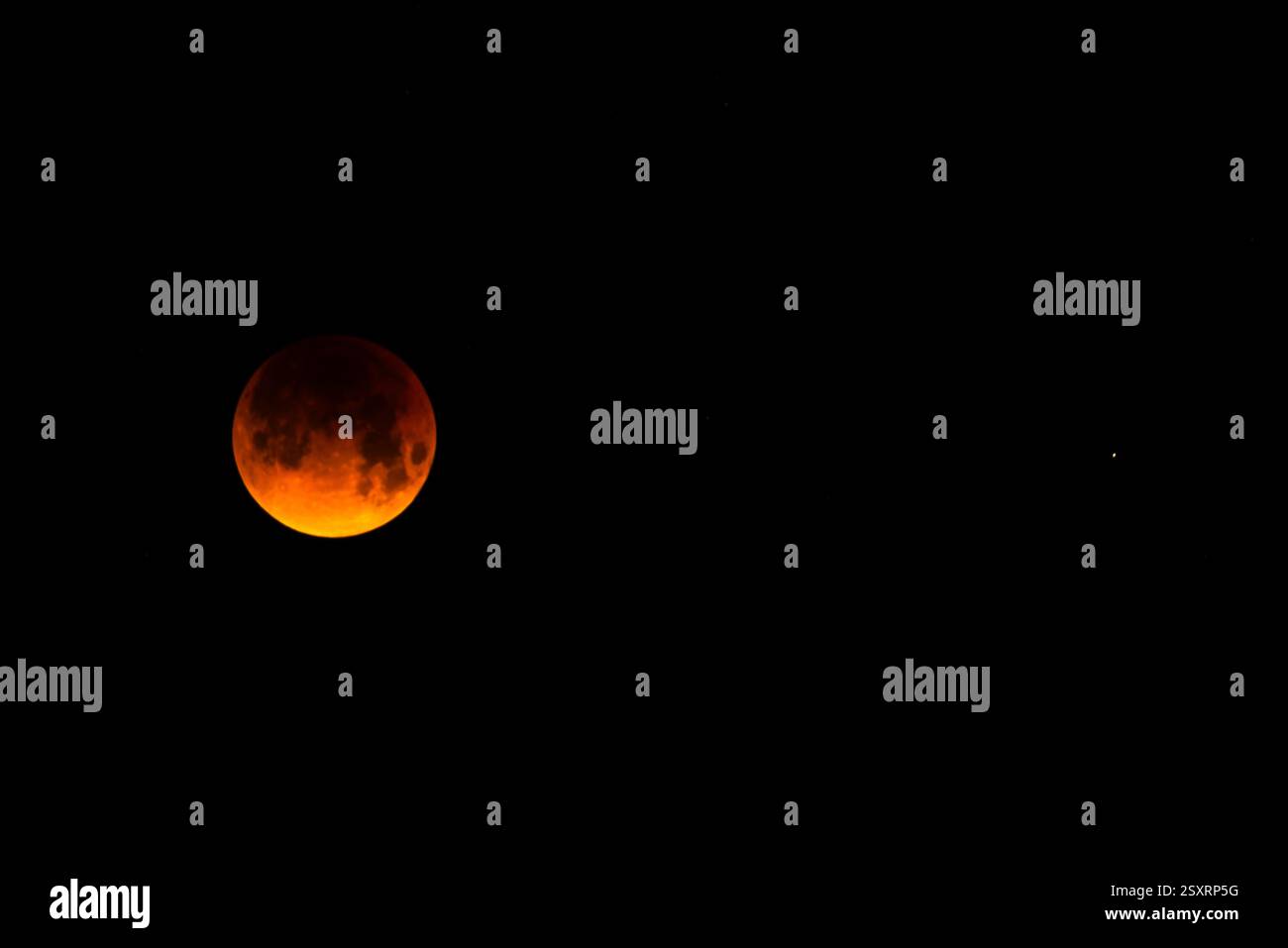 A glowing blood moon during a partial lunar eclipse at night. Stock Photo