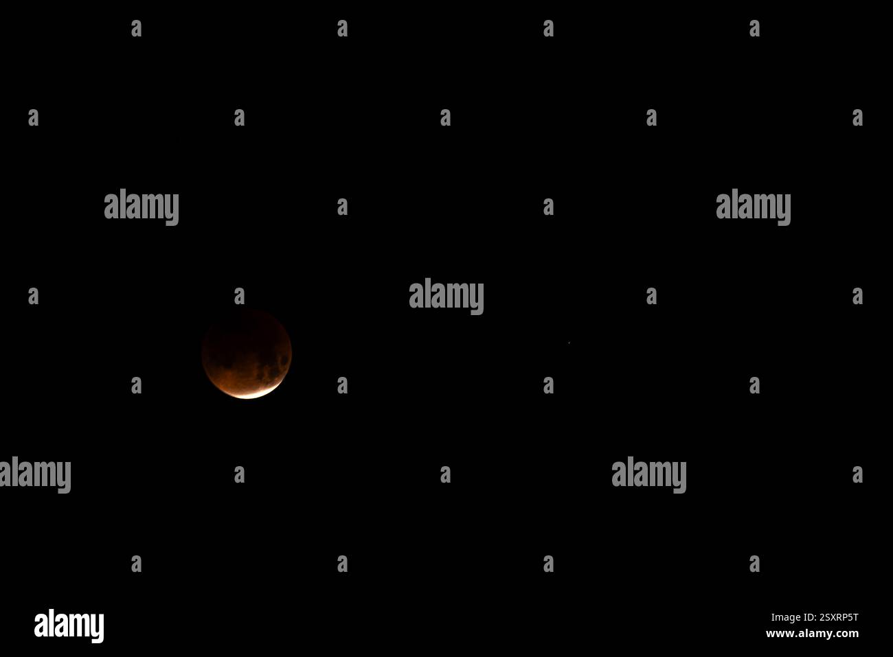 A glowing blood moon during a partial lunar eclipse at night. Stock Photo