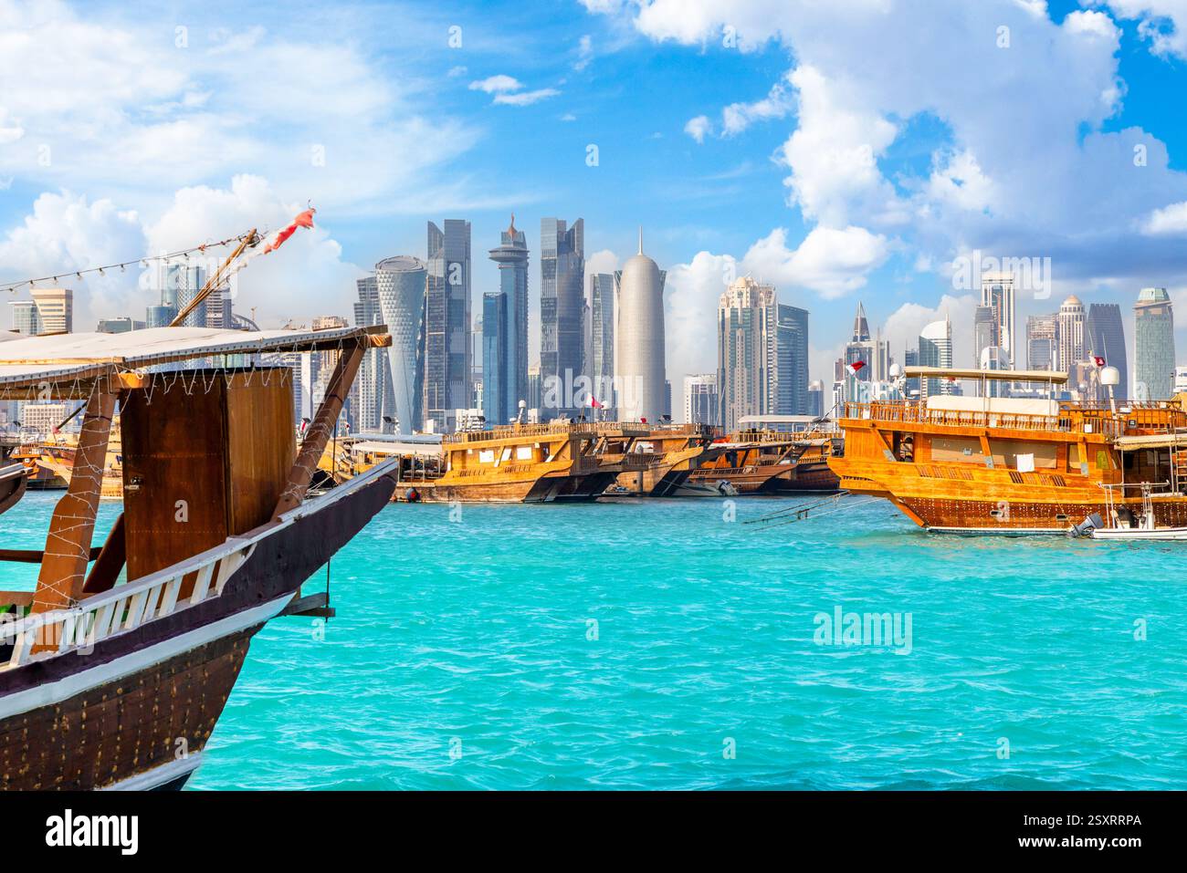 Traditional arab dhow fishermen boats anchored at pier with Doha modern ...