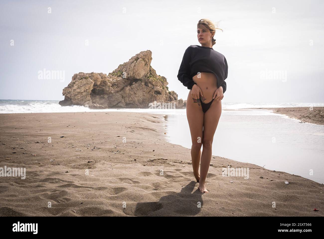 Gorgeous Venezuelan blonde bikini model revels in Alboran Sea's beauty, basking in beach bliss on holiday. Stock Photo