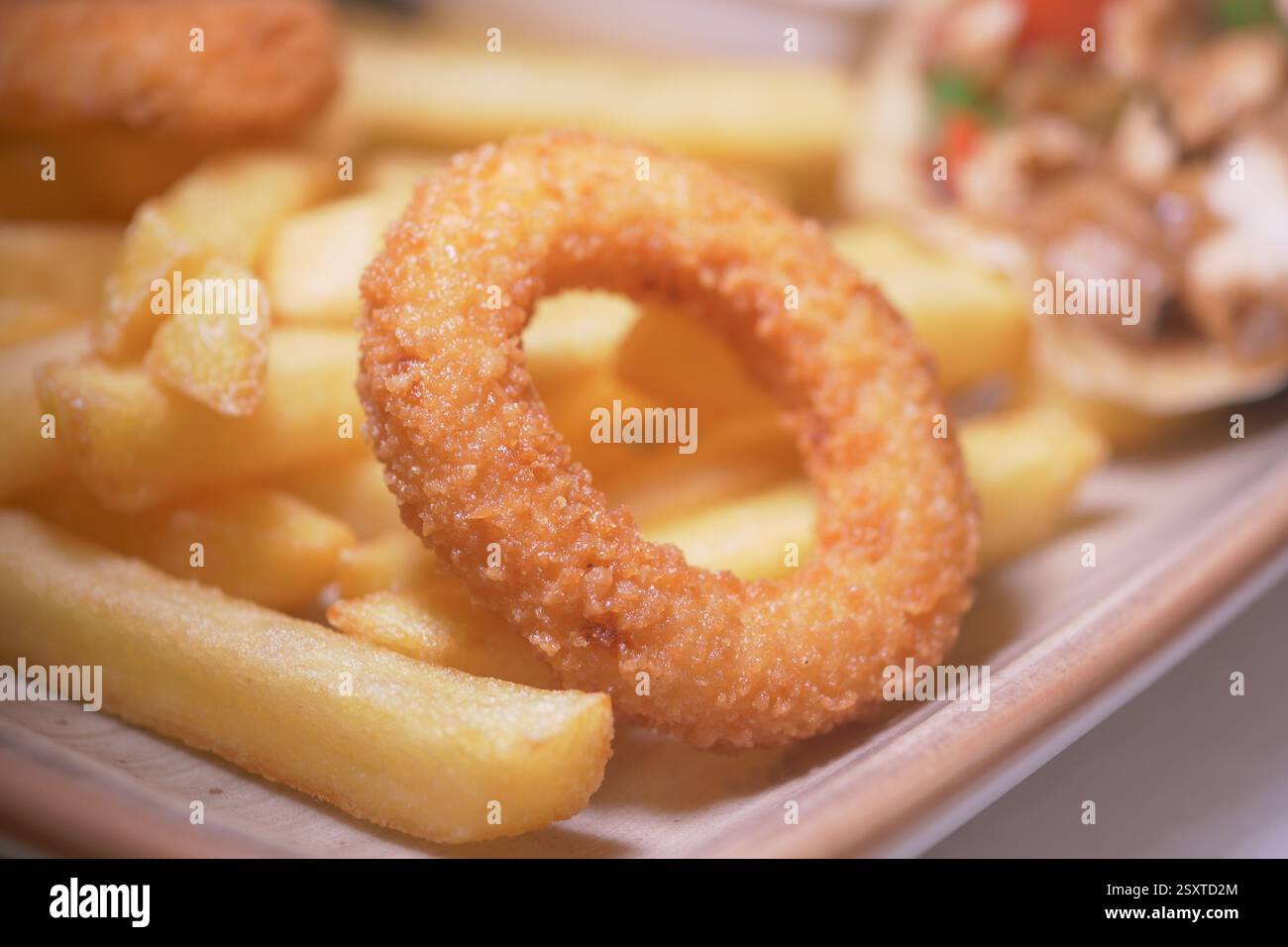 Crispy onion rings and golden fries served on a wooden plate Stock ...