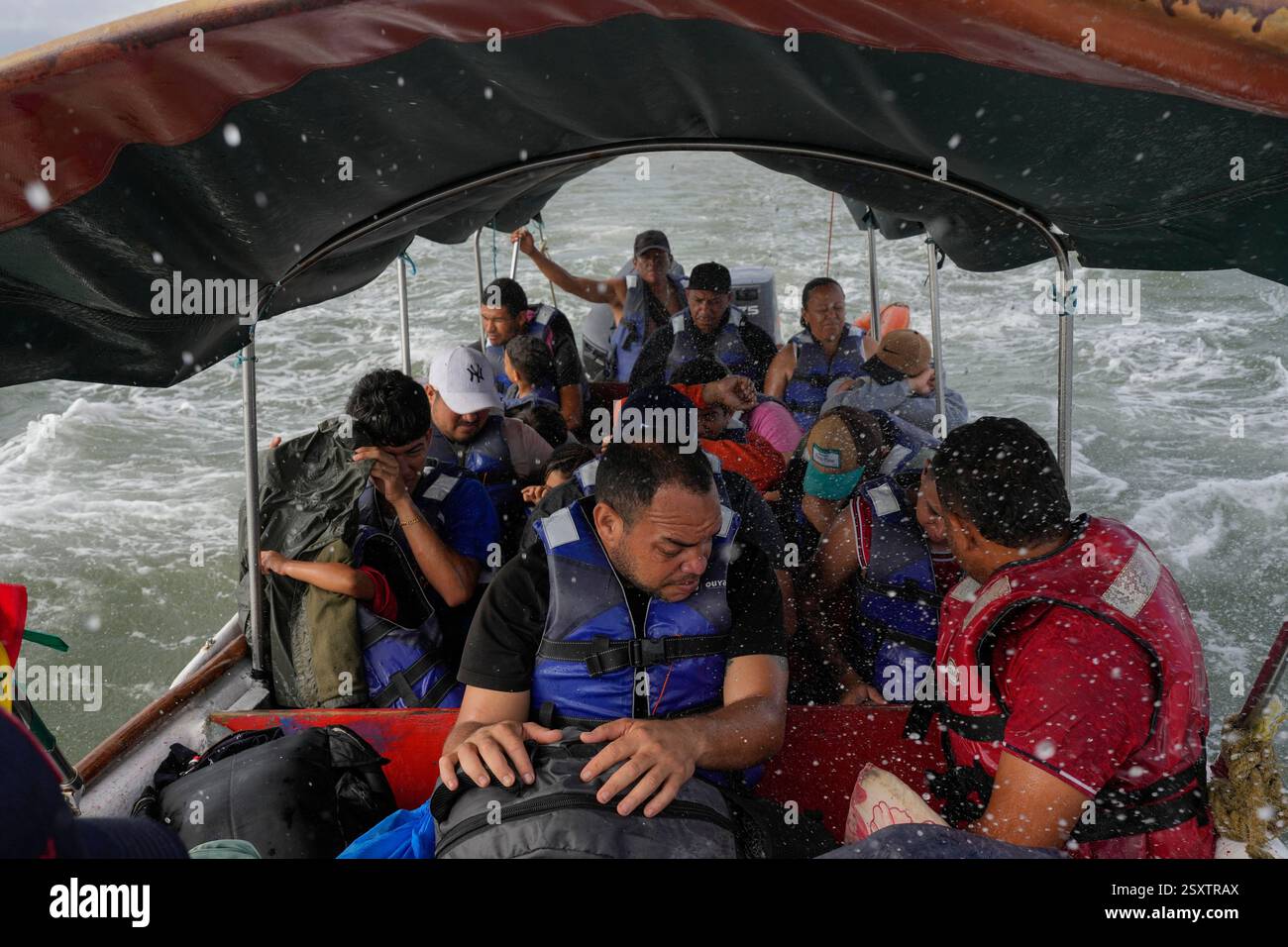 Luis Sanchez, center, sits with other Venezuelan migrants on a boat