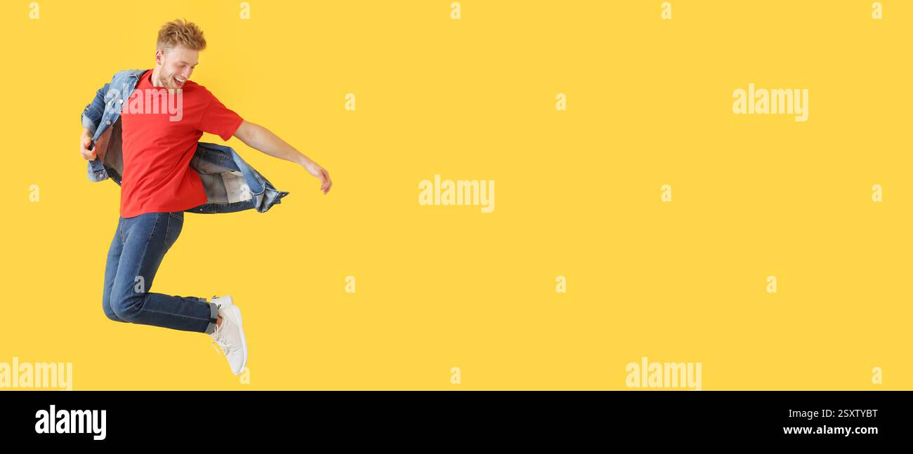 Jumping young man in denim clothes on yellow background with space for text Stock Photo