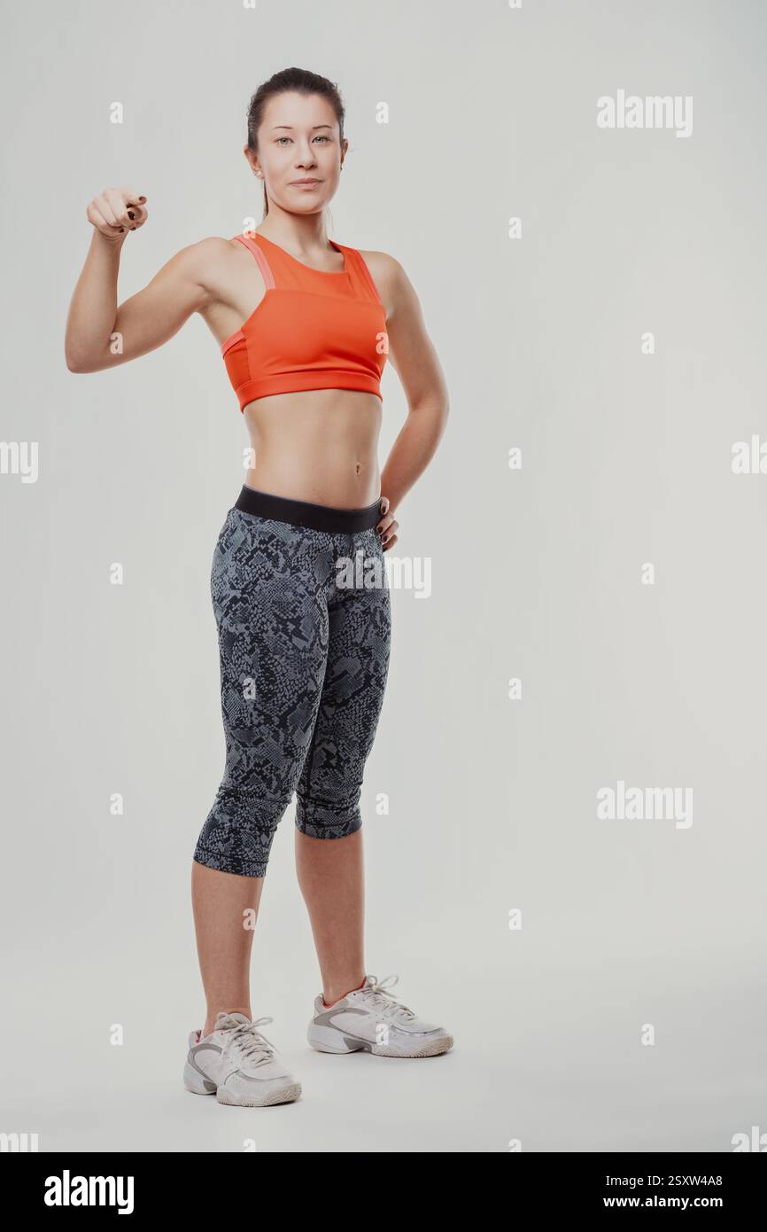 Full-length portrait of a confident young athletic woman flexing her ...