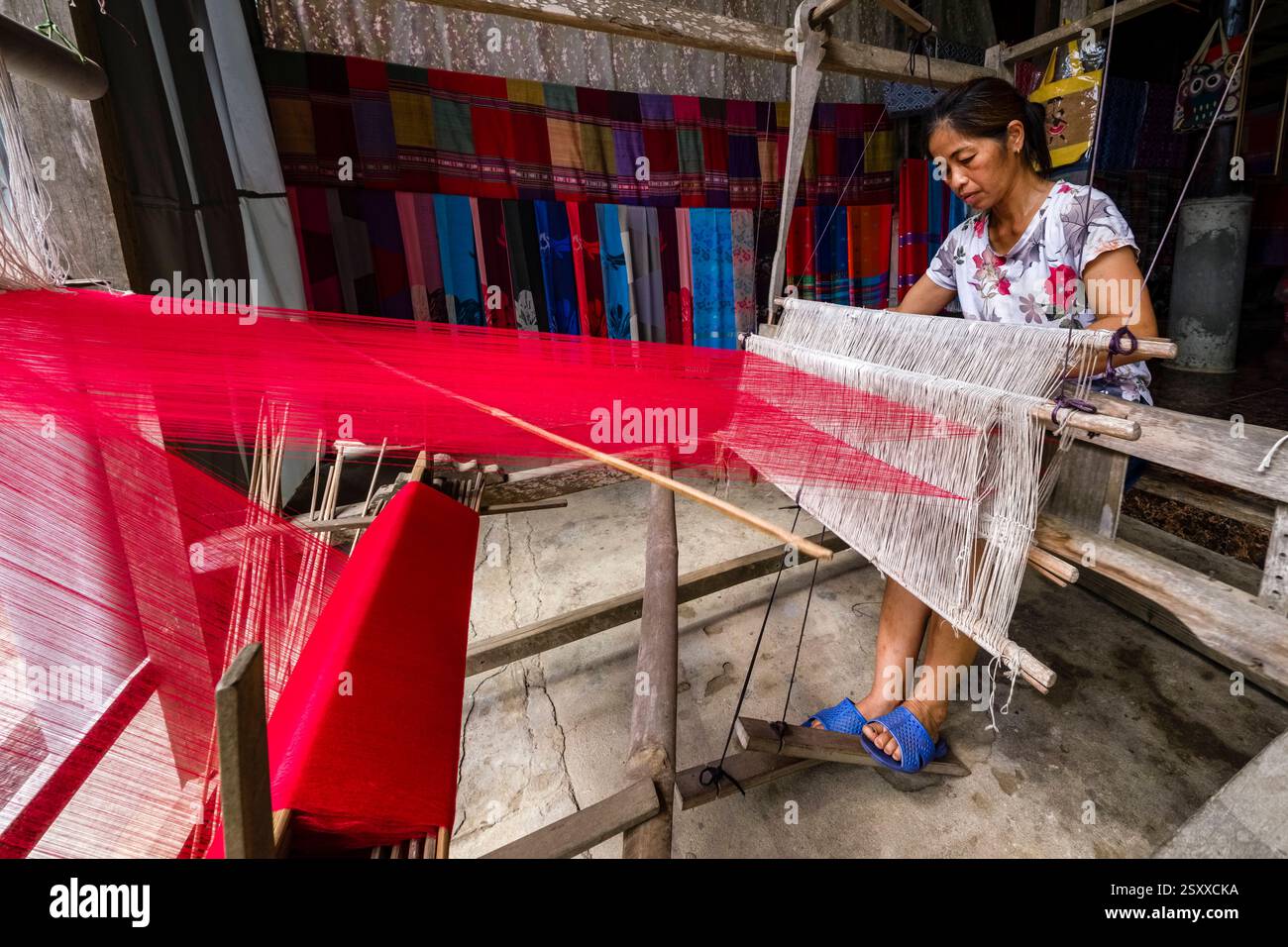 A local woman weaves fabric on a traditional wooden loom in Mai Chau ...