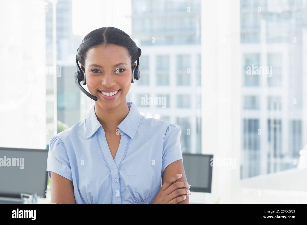 Wearing headset, businesswoman working in modern office, smiling while talking Stock Photo