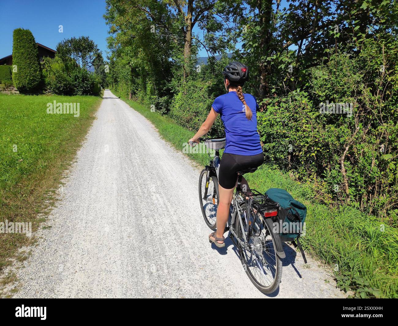 Female cyclist wearing helmet rides along river Salzach near Salzburg ...